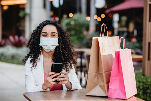 Young woman shopping at the mall during the pandemic of coronavirus and using cellphone