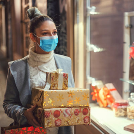 A girl holding a gifts in her hand and wearing a mask near gift shop