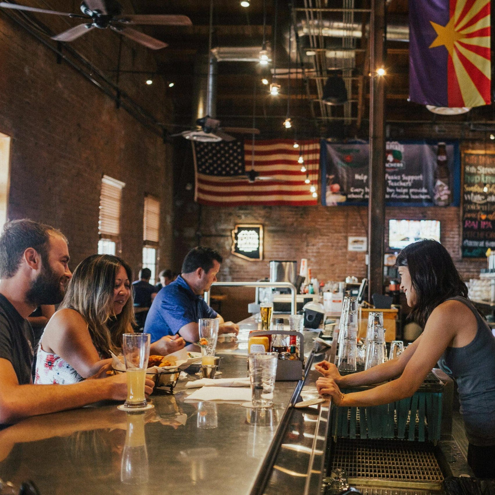 Restaurant patrons receiving service from bartender, demonstrating customer experience measurement in action.